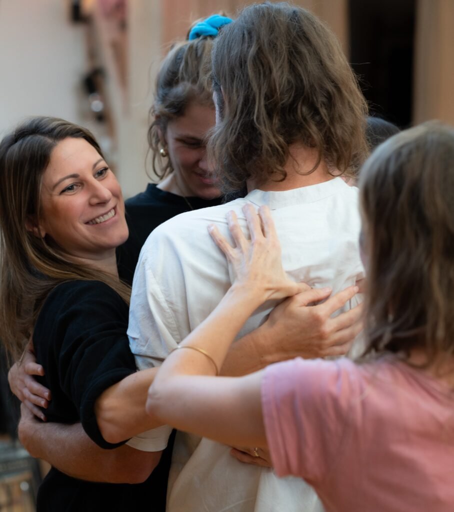 Drei Menschen in enger Umarmung während eines Coachings, Ausdruck von Vertrauen, Nähe und emotionaler Verbindung