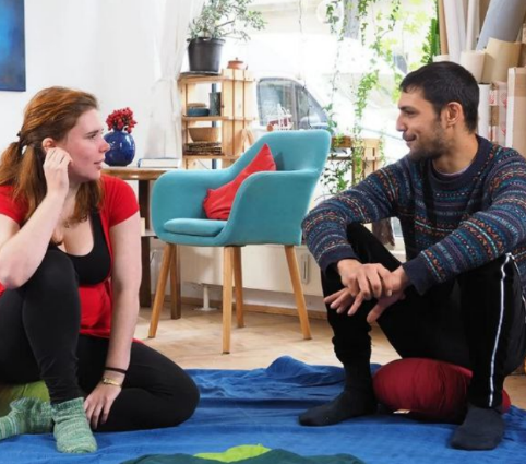 Zwei Personen sitzen sich in einem Coaching gegenüber und sprechen ruhig, präsent und aufmerksam miteinander.