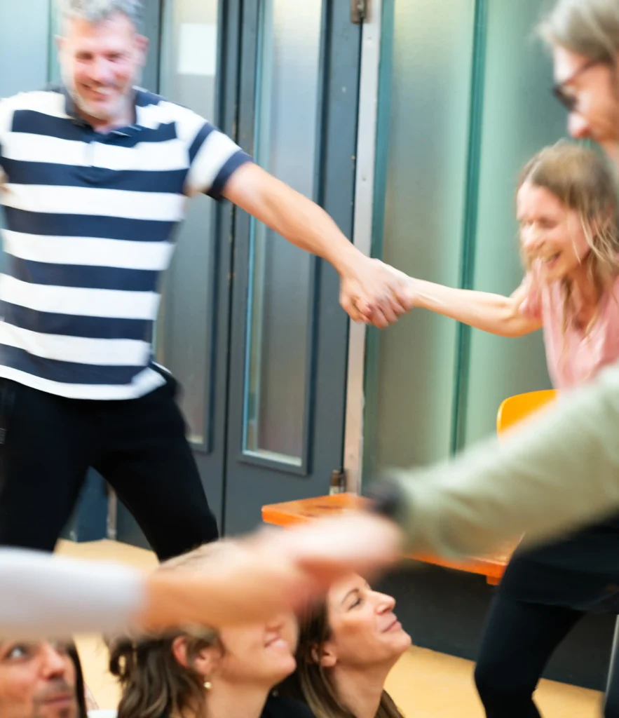 Gruppe von Menschen lacht, hält sich an den Händen – symbolisiert Herz-, Kopf- und Bauchverbindung, Lebensfreude und Präsenz