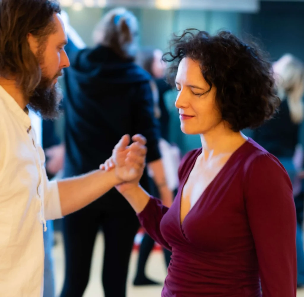Frau und Mann in achtsamem Kontakt, Frau hält die Hand des Mannes, Augen geschlossen – symbolisiert Herzöffnung, Vertrauen und tiefe Verbindung