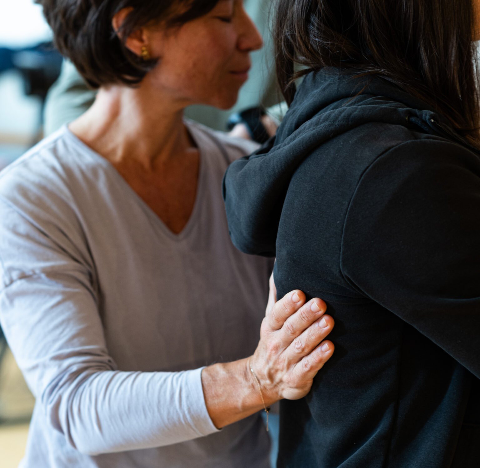 Coaching-Session: Eine Person legt liebevoll die Hand auf den Rücken einer anderen, achtsam und unterstützend.