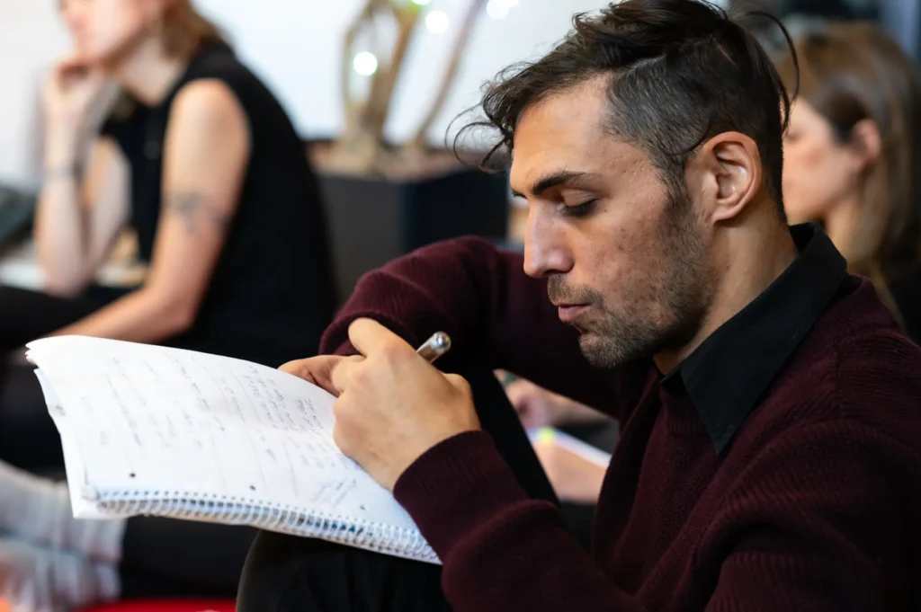 Benjamin Malik im Workshop, Papier und Stift in der Hand, konzentriert und präsent, verkörpert psychologische Tiefe und Transformation